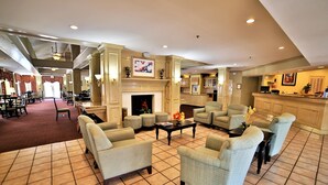 A spacious lobby with a fireplace, comfortable seating, and a reception area.