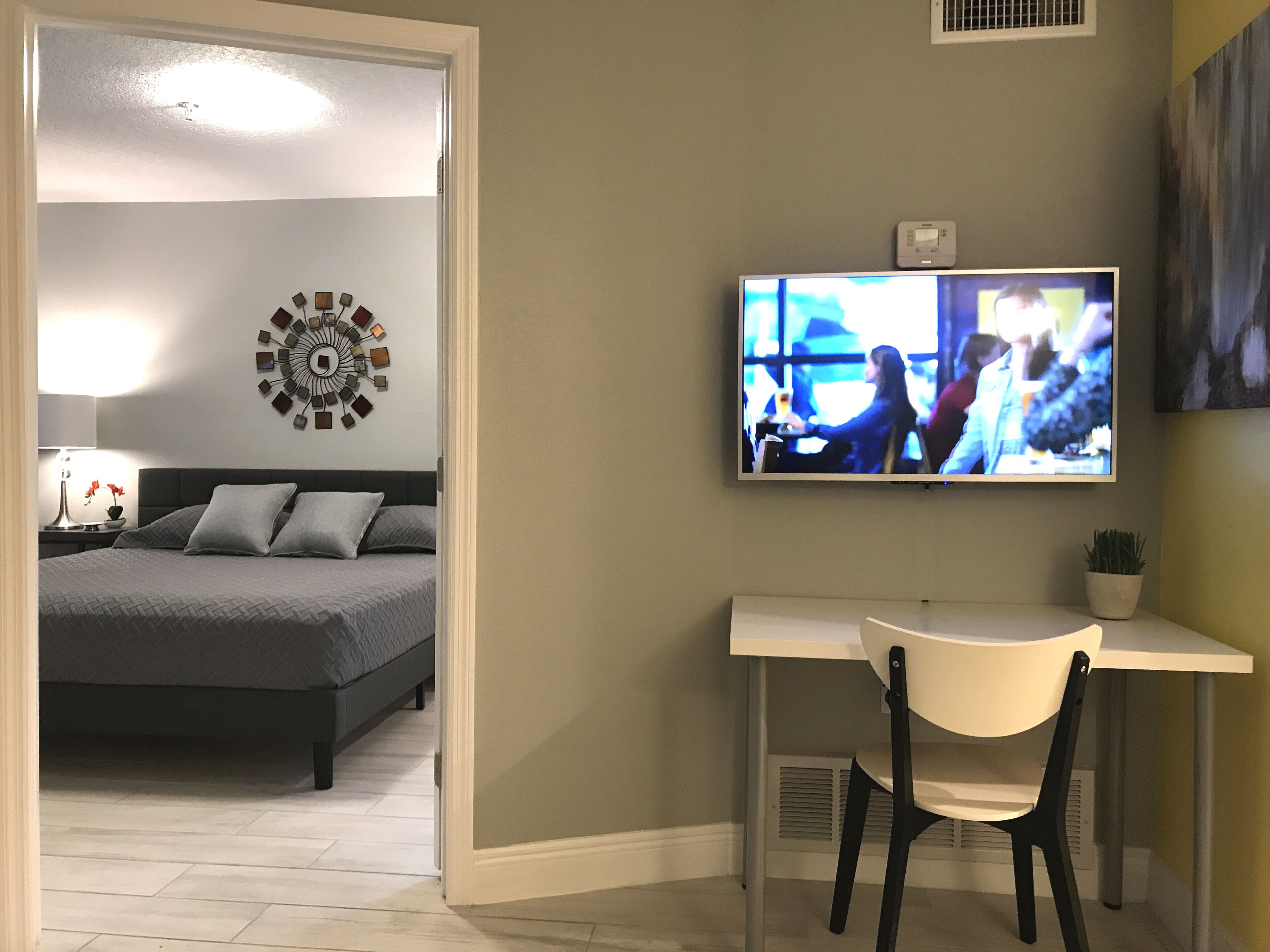 A bedroom with a bed, a desk, and a TV.