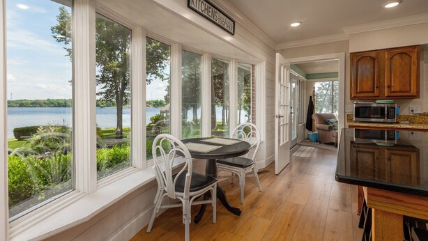 A kitchen with a view of a lake, white chairs, and a dining table.