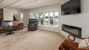 A living room with a fireplace, a large TV, and a view of the outdoors.