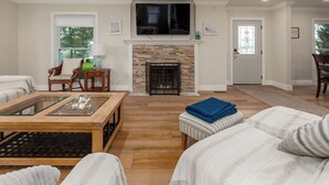 A living room with a fireplace, a television, and a dining area.