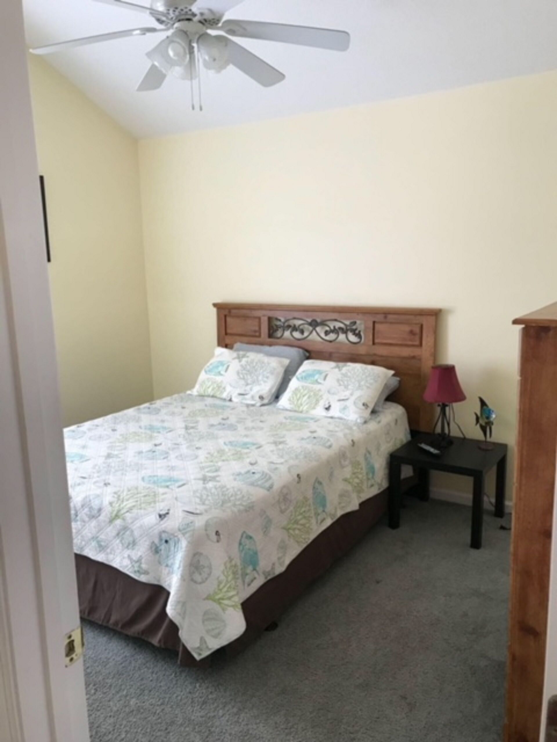 A bedroom with a bed, a nightstand, a lamp, and a ceiling fan.