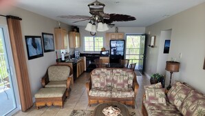 A spacious living room with a large sofa, two armchairs, a coffee table, and a dining area with a kitchen in the background. - Middle Bass Island-Premium Lakefront Condo with Large Lakefront Covered Patio  (Middle Bass Island)