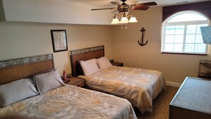 A hotel room with two beds, a ceiling fan, a window with a view, and a small table. - Middle Bass Island-Premium Lakefront Condo with Large Lakefront Covered Patio  (Middle Bass Island)