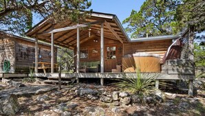 Eine rustikale Holzhütte mit Veranda und Whirlpool.