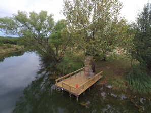 A wooden dock extending into a calm body of water, surrounded by trees and vegetation. - Love Shack | Romantic Cabin w/ Hot Tub & Creek (Pipe Creek)