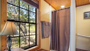 Ein Badezimmer mit einem großen Fenster, einem Handtuchhalter und einer Holzbank.