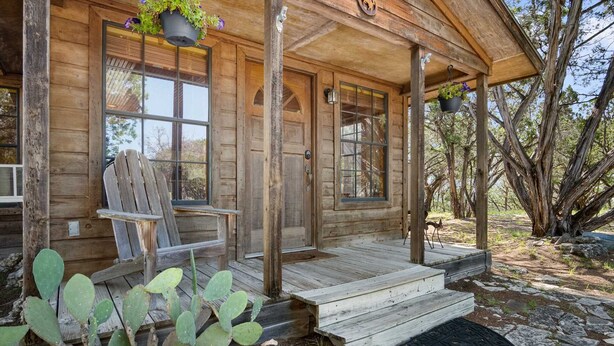 Eine Holzhütte mit Veranda, einer Kakteenpflanze und einem Stuhl.