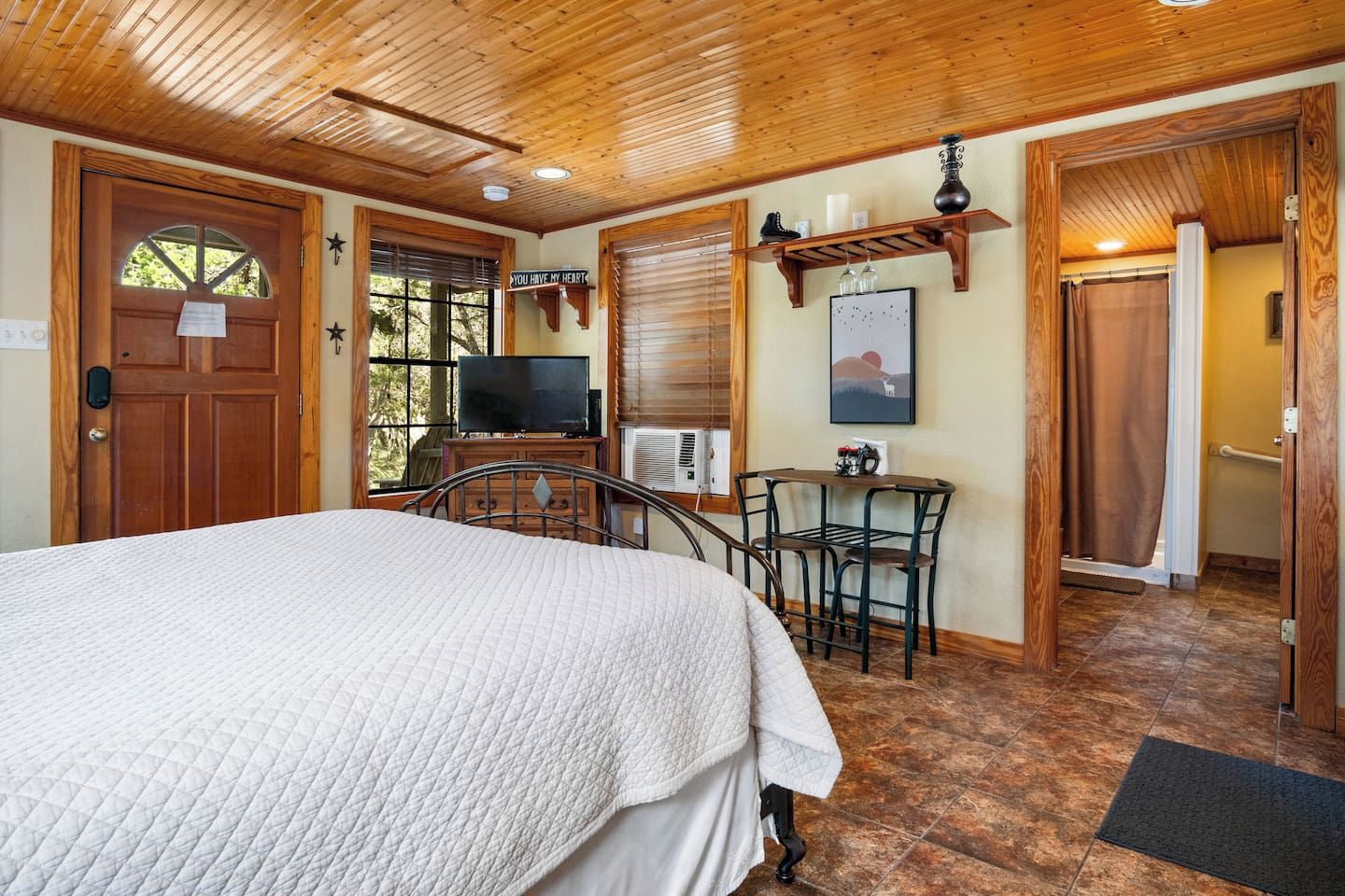 Un dormitorio con cama, televisión, escritorio y silla.