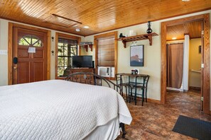 A bedroom with a bed, a television, a desk, and a chair.