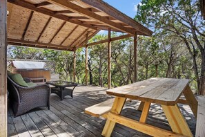 A covered outdoor area with a picnic table and wicker furniture.