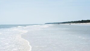 Ein Strand mit weitem, sandigen Ufer und sanften Wellen.