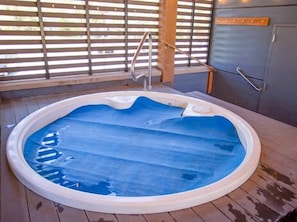 Relax in a hot tub on a spacious deck with a bench and ladder.