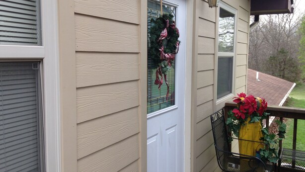 A house exterior with beige siding, a white door, and a window with a wreath. - Private one bedroom, one bathroom, apartment with private entrance & hot tub (Branson)