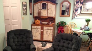 A living room with two black armchairs, a wooden cabinet with a mirror, and a small table with a plant. - Private one bedroom, one bathroom, apartment with private entrance & hot tub (Branson)