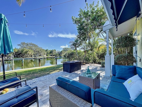 A patio area with outdoor furniture, a pond, and a view of a lake.