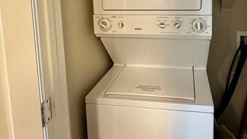 A compact washer and dryer unit with a control panel, located in a small laundry room with a tiled floor.