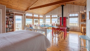 Um quarto acolhedor com uma cama grande, uma mesa de jantar e vista para o mar.