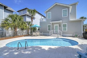 A residential property with a swimming pool, a covered patio, and a two-story house.