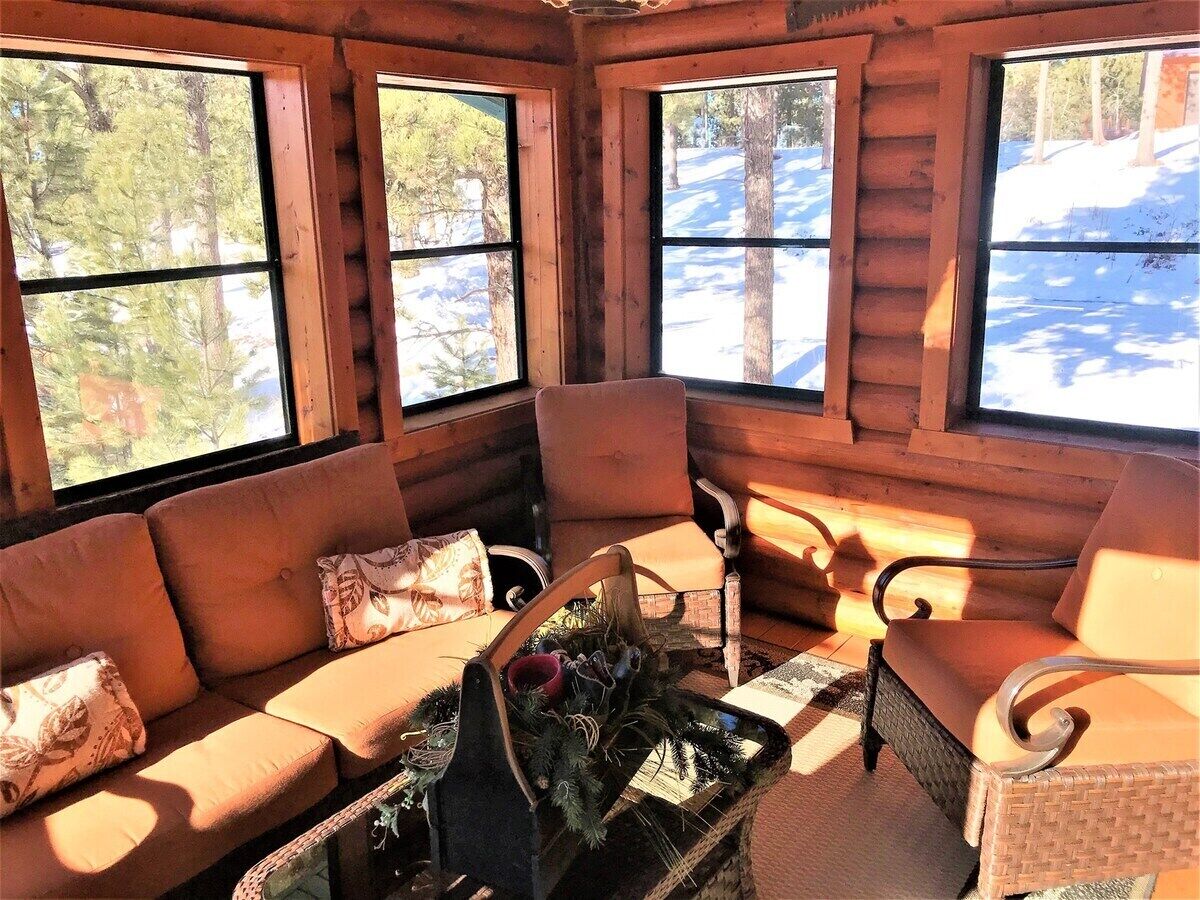 A log cabin interior with a sofa, chairs, and a fireplace.