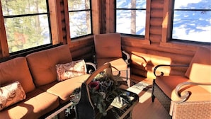 A log cabin interior with a sofa, chairs, and a fireplace.