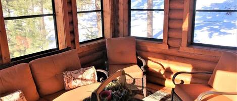 A log cabin interior with a sofa, chairs, and a fireplace.