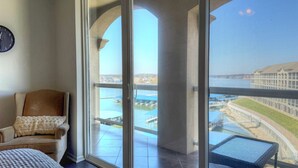 A room with a view of a waterfront, a chair, and a table.