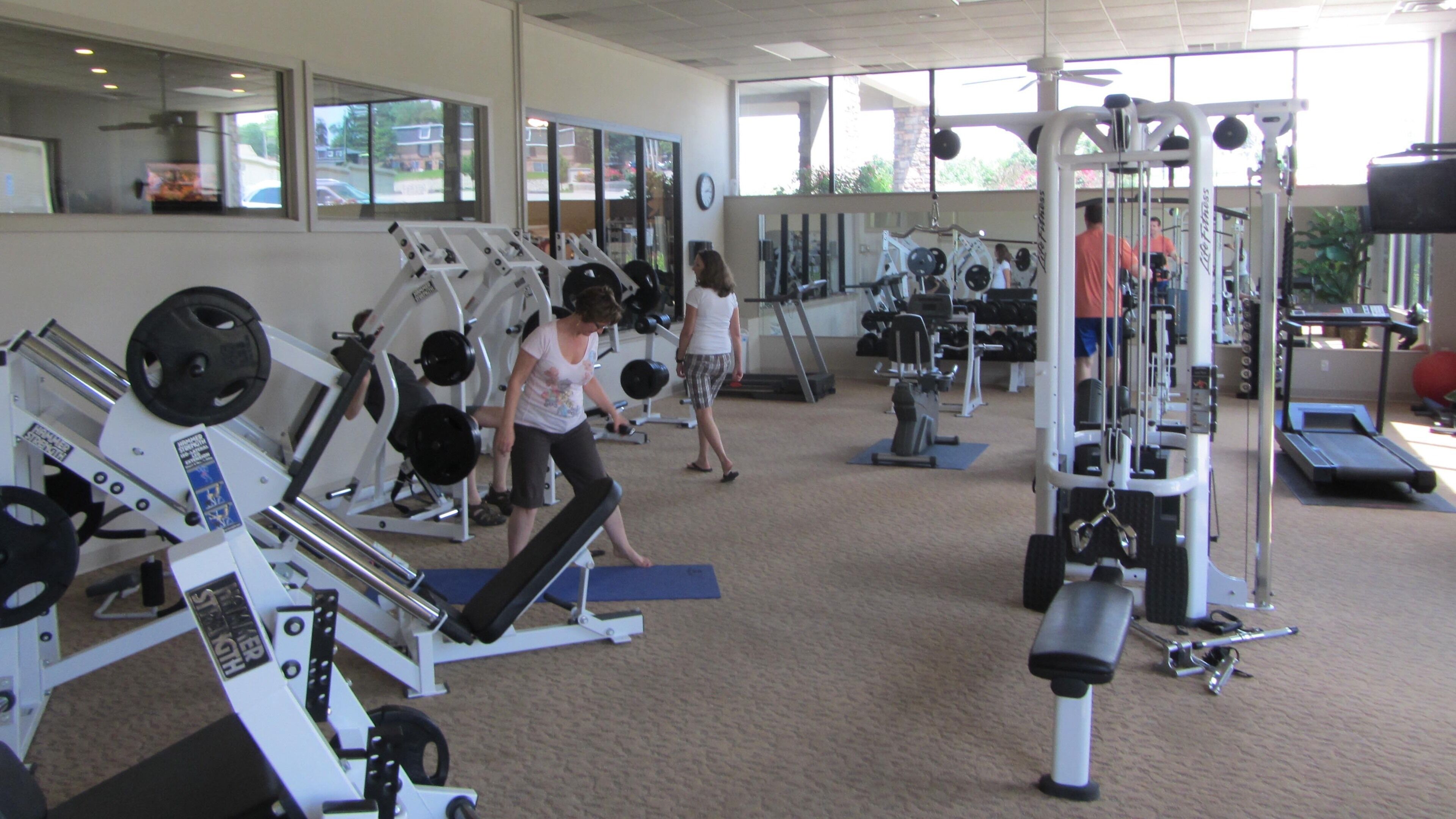 Une salle de sport équipée de divers appareils d’exercice, notamment des machines de musculation, des tapis de course et des poids libres.