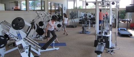 Une salle de sport équipée de divers appareils d’exercice, notamment des machines de musculation, des tapis de course et des poids libres.