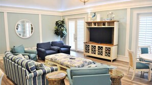 A living room with a sofa set, a coffee table, a television, and a dining area with chairs.