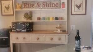 A kitchen counter with a microwave, a bottle of wine, and a sign that reads "Rise & Shine".