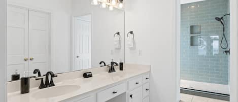 A modern bathroom with two sinks, a large mirror, and a shower area with blue tiles.