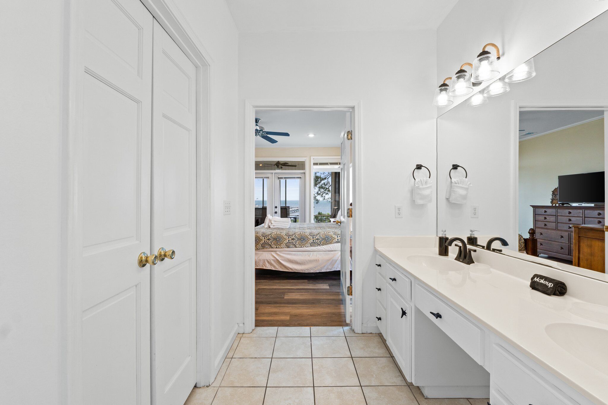 A modern bathroom with a large mirror, white vanity, and a shower area.
