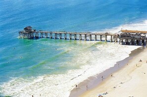 An aerial view of a beach with a pier extending into the ocean. - Newly Remodeled, ocean view condo on top floor at Spanish Main (Cocoa Beach)