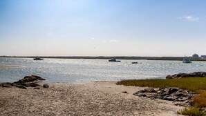 A beach with a sandy shore, calm water, and boats in the distance. - Relaxing Hampton Beach Vacation Home (Hampton)