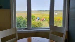 A room with a large window overlooking a field with chairs and a table. - Relaxing Hampton Beach Vacation Home (Hampton)
