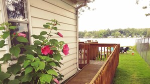 A wooden deck leading to a house with a window reflecting trees. - Vacation at Garver Lake ~ Private Beach For Your Enjoyment! (Edwardsburg)