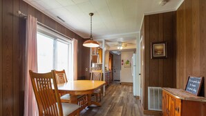A wooden-paneled kitchen with a dining table, chairs, and a hanging light fixture. - Vacation at Garver Lake ~ Private Beach For Your Enjoyment! (Edwardsburg)