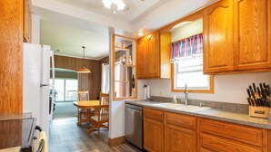 A kitchen with wooden cabinets, a dishwasher, a sink, and a knife block. - Vacation at Garver Lake ~ Private Beach For Your Enjoyment! (Edwardsburg)