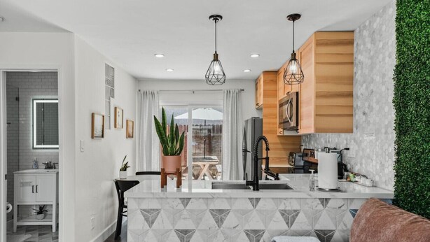 A modern kitchen with a central island, wooden cabinets, and pendant lighting.