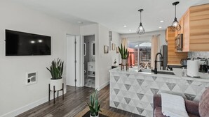 A modern kitchen with a marble backsplash, wooden cabinets, and pendant lighting.