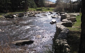 A river flowing through a stone-lined path with rocks and greenery.
