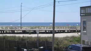 Un espace de stationnement avec un véhicule, une clôture en bois et une plage en arrière-plan.