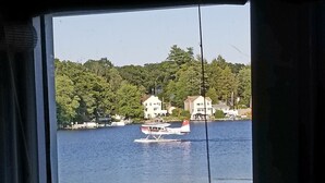 A view of a lake with a house and a small airplane on the water. - The Guest Cottage in Paradise. (Northwood)