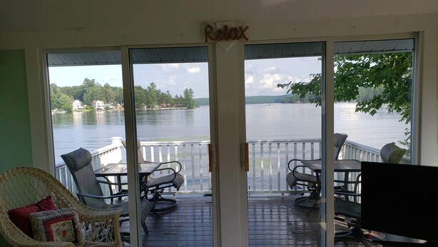 A room with a view of a lake, a balcony with outdoor furniture, and a sign that reads "Relax". - The Guest Cottage in Paradise. (Northwood)