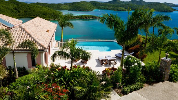 A pool area with lounge chairs, surrounded by lush greenery and a view of a turquoise lake and mountains. - Heaven's Gate - Off Grid Ocean View Villa (Coral Bay)