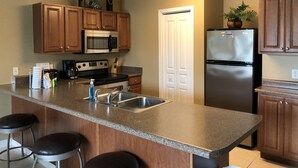 A kitchen with wooden cabinets, a stainless steel refrigerator, a microwave, a stove, and a sink. - Self Checkin/Out | Family Friendly | Perfect Location | Free WiFi  (Miramar Beach)