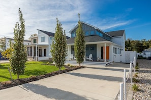 A modern two-story house with a covered porch, a well-maintained lawn, and a clear sky. - Private Pool Fire Pit Rehoboth Beach Home w/ Parking (Rehoboth Beach)