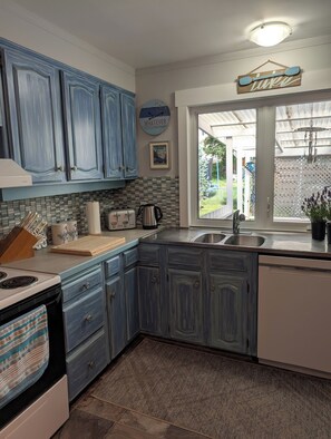 Una cocina con armarios azules, una estufa, un fregadero y una ventana con vistas al exterior.