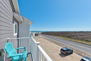 A balcony with two chairs, a road, and a parking area.